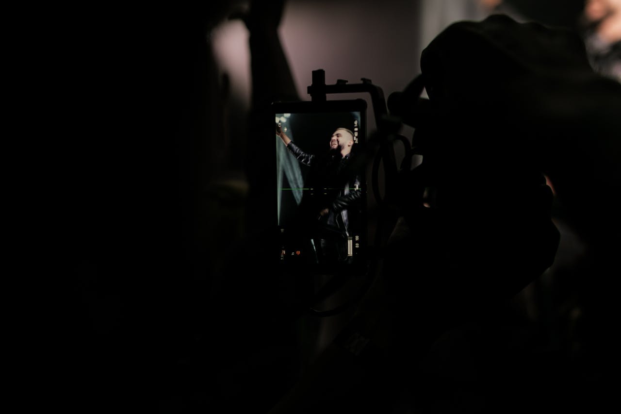 about-us A performer on stage captured through a smartphone at a dark, energetic concert.